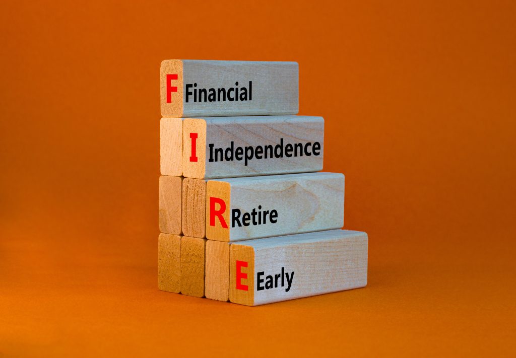 FIRE financial independence retire early symbol. Concept words FIRE financial independence retire early on blocks. Orange background. Business FIRE financial independence retire early concept.