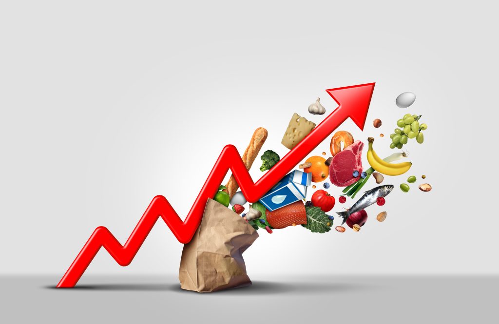 Steigende Lebensmittelkosten und steigende Preise für Lebensmittel im Supermarkt als Konzept für eine Inflationsfinanzkrise, die aus einer Tüte in Form eines Pfeils eines Finanzdiagramms mit 3D-Render-Elementen hervorgeht.